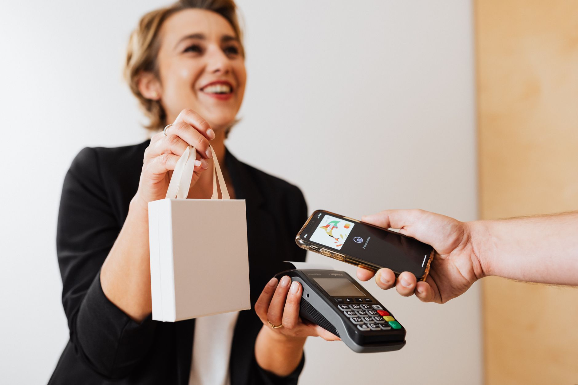 Caissière souriante effectue un achat avec un paiement mobile sans contact dans un magasin moderne.