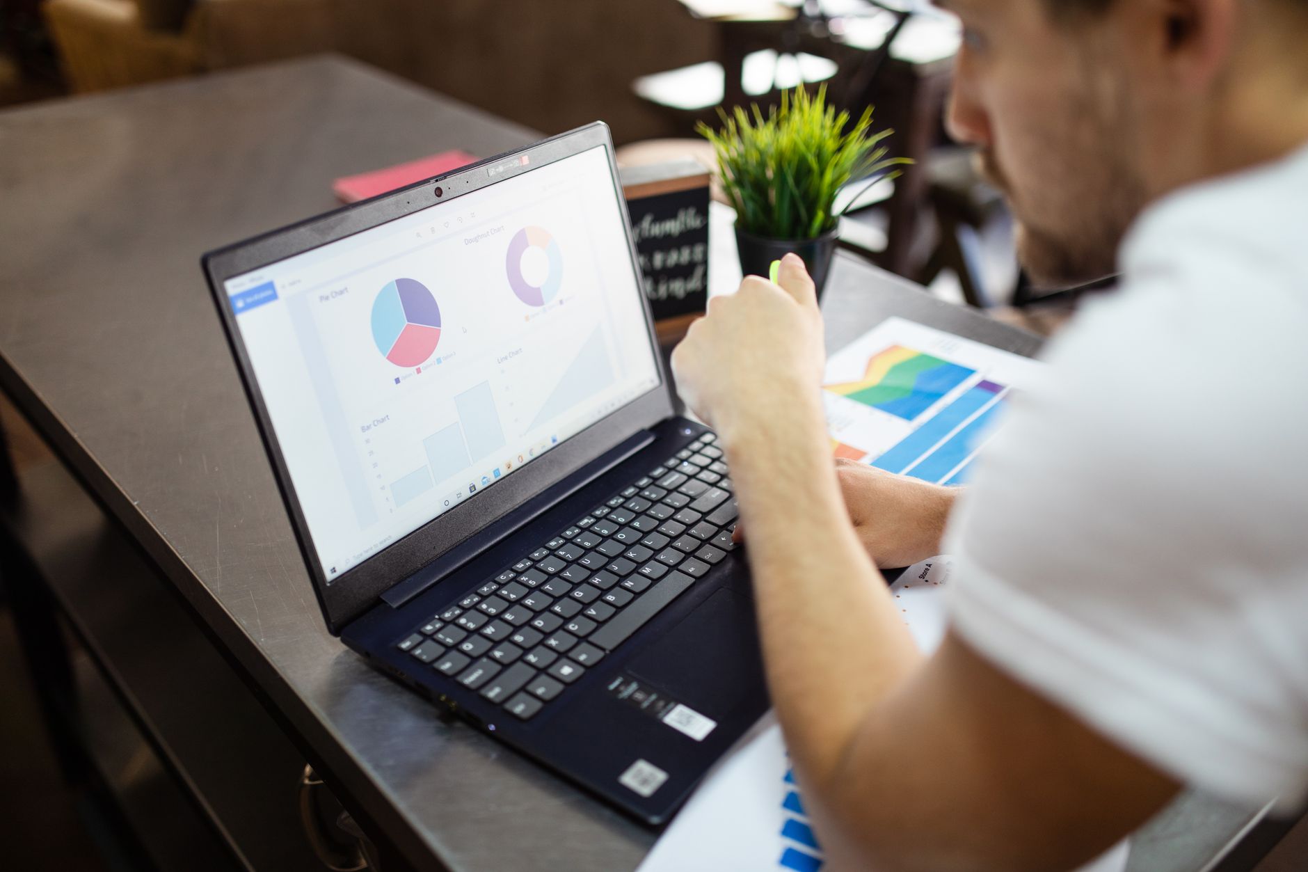 Une personne consulte des graphiques et des statistiques sur l’écran d’un ordinateur portable posé sur un bureau.